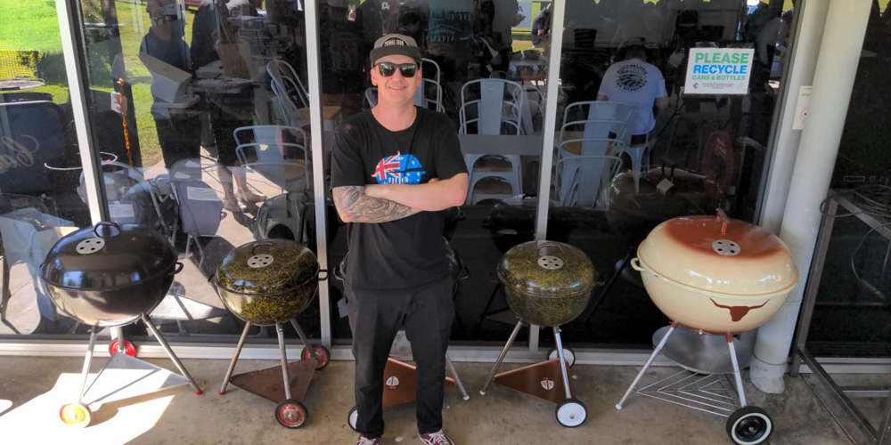 Chris Bray standing with his collection of vintage Weber kettles
