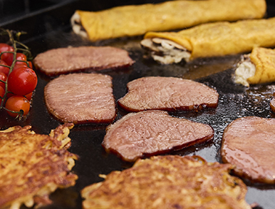 Steak, rosti and wraps cooking on the flat hotplate