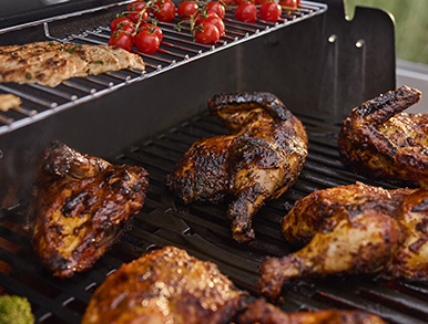 Chicken quarters and cherry tomatoes grilling