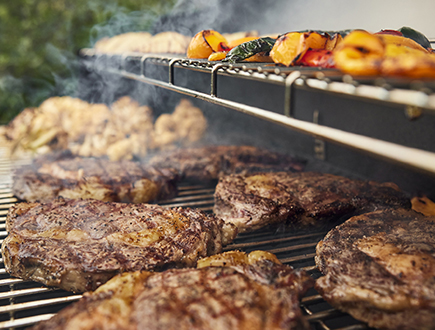Steaks and vegetables smoking on the grill
