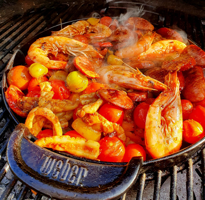 Seafood platter of prawns, calamari and tomatoes cooking in a Weber grill pan