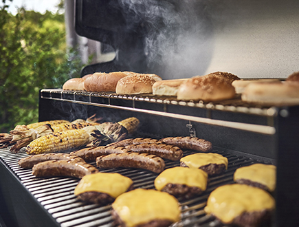 Burgers, sausages, corn and buns grilling together