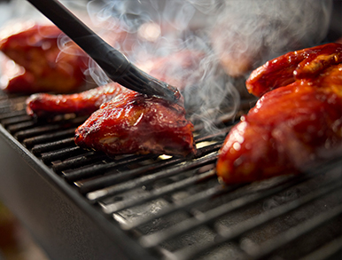 Glazed chicken wings being basted on the grill