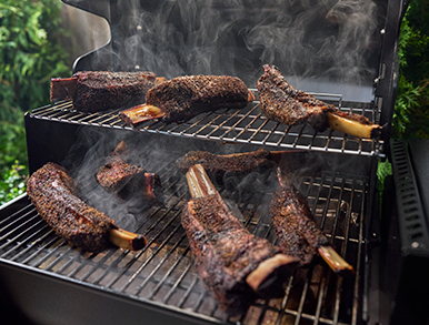 Beef short ribs smoking on the grill