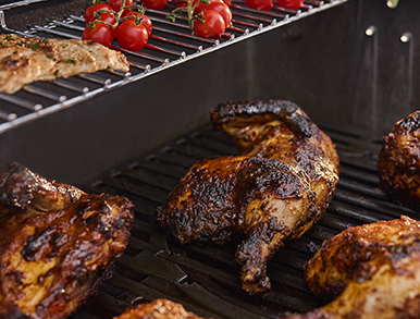 Whole chicken halves roasting on the grill