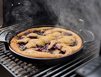 Berry cobbler baking in a cast iron skillet on the grill