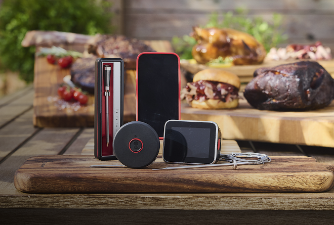 Eine Reihe von smarten Zubeh&ouml;rprodukten von Weber mit Grillgut im Hintergrund.