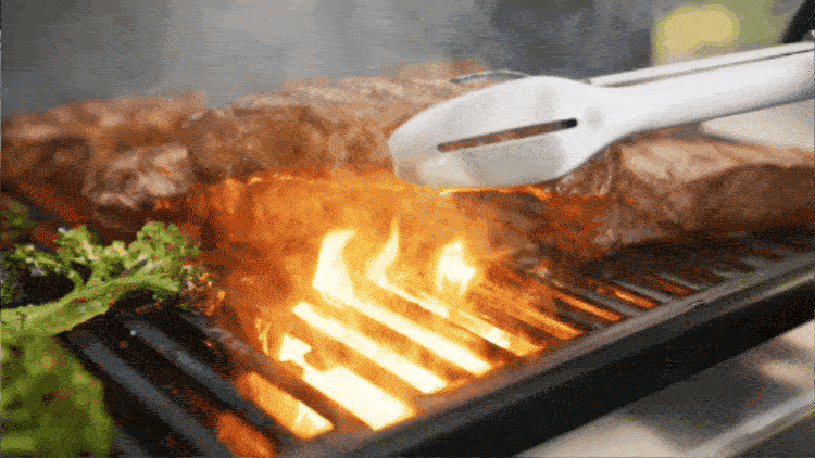 Close-up of grilling steak on a barbecue, with flames licking the meat and fresh greens on the side, creating a smoky atmosphere.