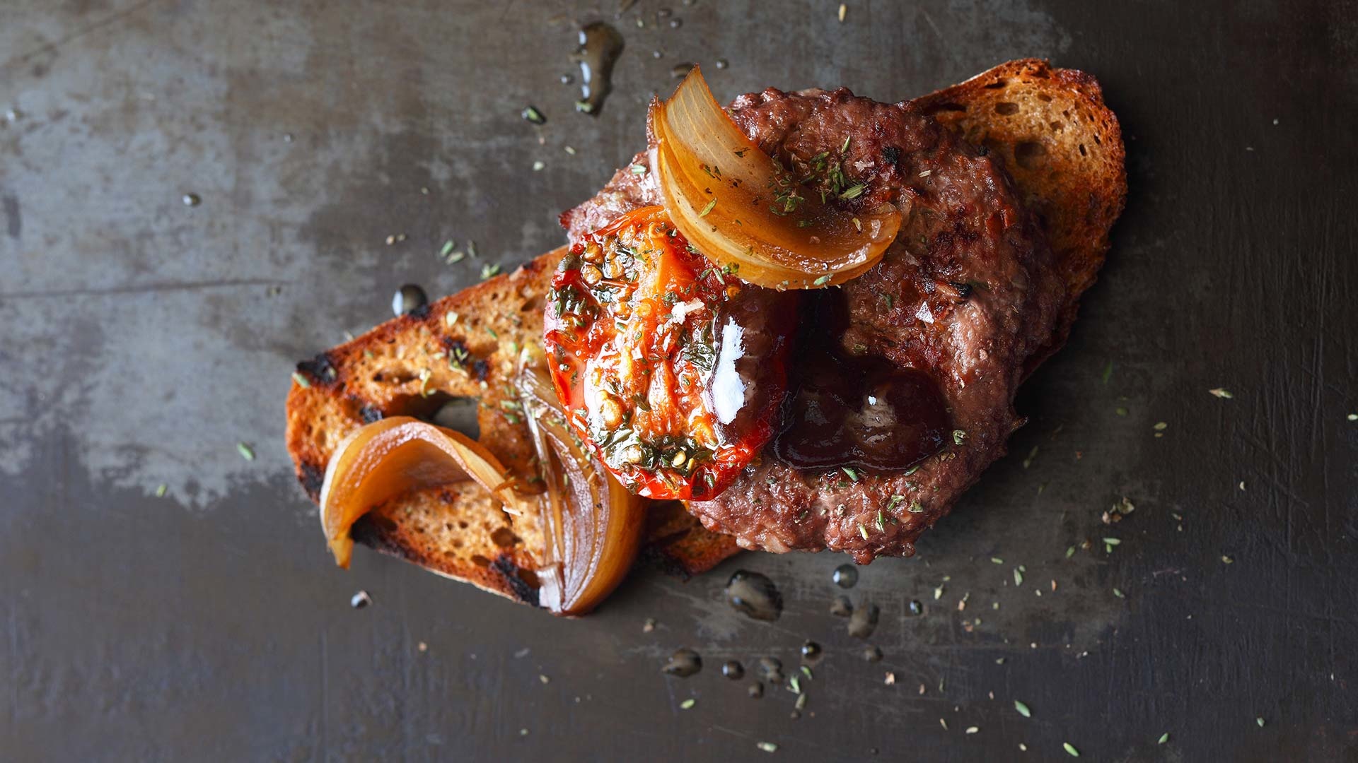  Saftiger Beef-Burger mit aromatischen D&ouml;rrtomaten auf dem R&ouml;stbrot mit s&uuml;&szlig;en Zwiebeln und BBQ-Sauce


