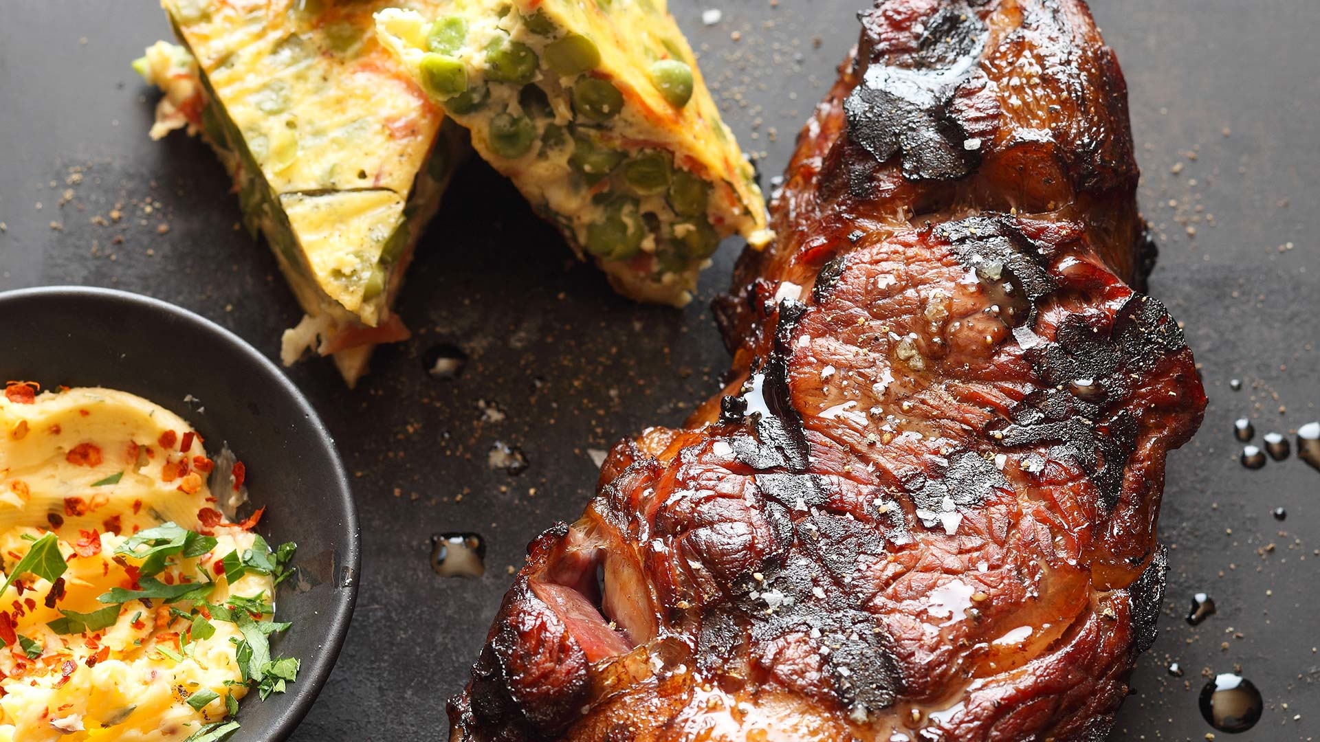  Tranchen vom Rinderr&uuml;ckensteak, serviert mit Chili-Kr&auml;uter-Butter, Erbsen-Fritatta mit Parmaschinken und Basilikum


