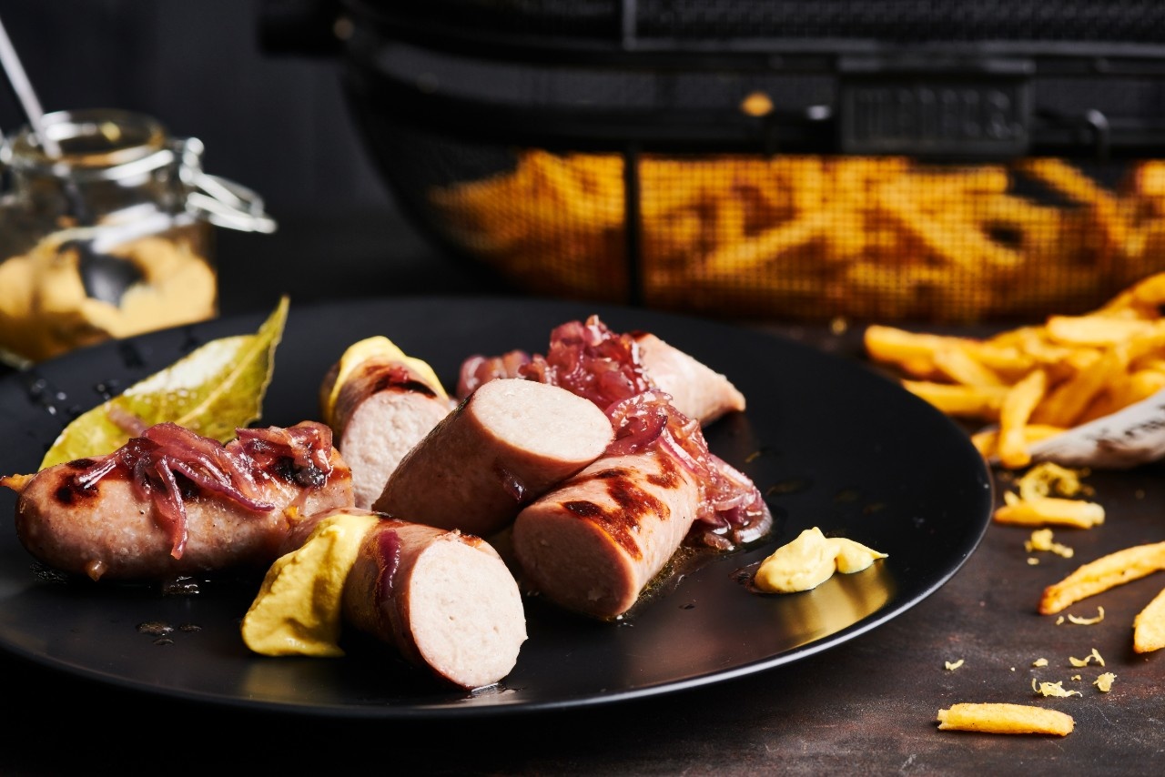  Rohe Schweinsbratwurst mit cremig eingekochtem Biersud serviert, dazu knusprige Pommes Frites „Grillmeister-Style" aus dem Drehkorb

